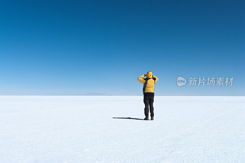 游客站在玻利维亚高原乌尤尼盐沼上