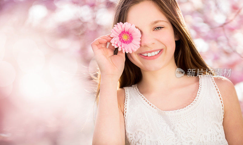 一个兴高采烈的女孩，面前捧着一朵粉红色的花
