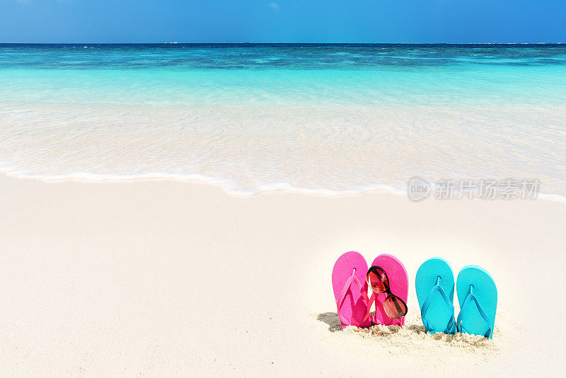 沙滩上的彩色人字拖和太阳镜