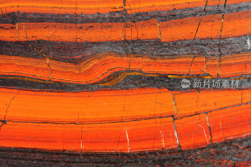 破裂的红色和橙色岩石被称为虎铁赤铁矿