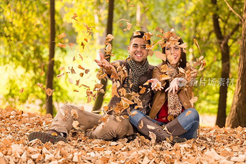 年轻夫妇在公园里扔树叶