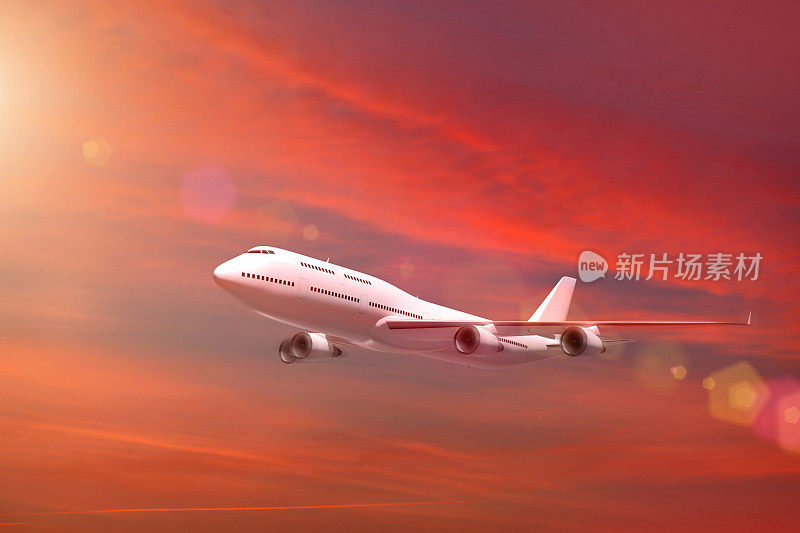 白色的飞机在夕阳的红色天空中飞行