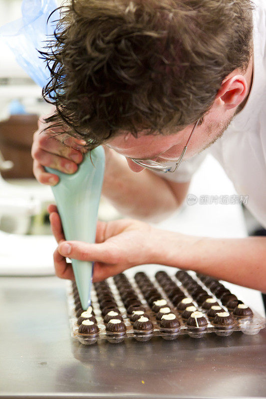 厨师在制作松露之前先将奶油放入巧克力模具中
