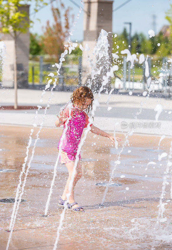 小女孩在喷泉在户外水花公园玩