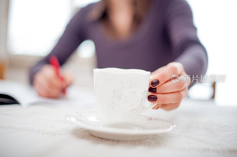 年轻女子在写音符的时候喝咖啡休息-双手合十