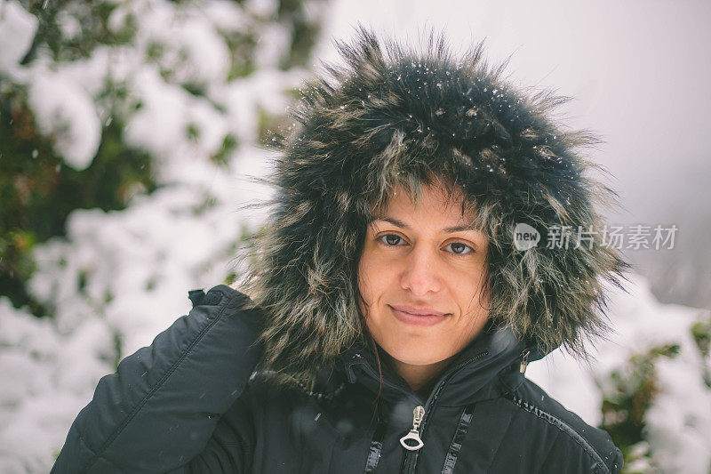 冬天的女人在寒冷的冬日里，在雪地里仰望着快乐的微笑。