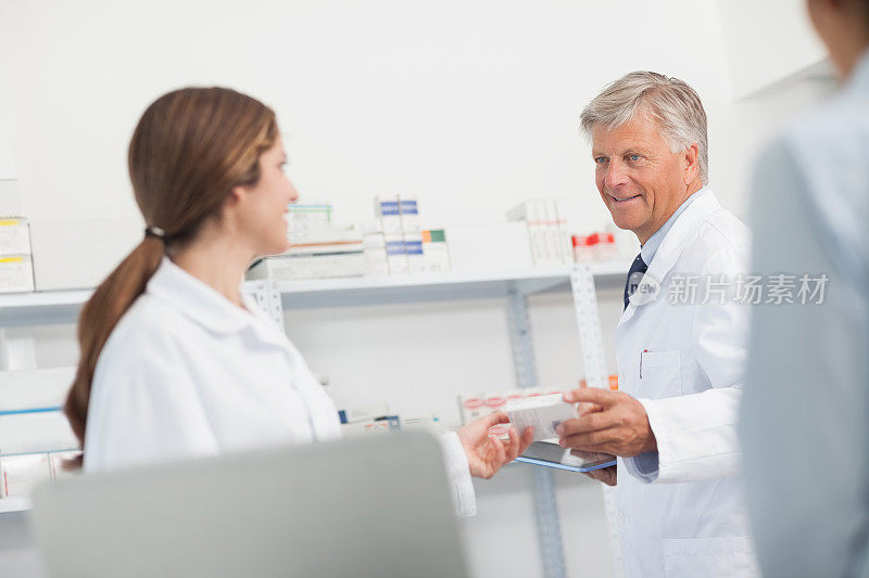 微笑的药剂师给他的同事一盒药丸