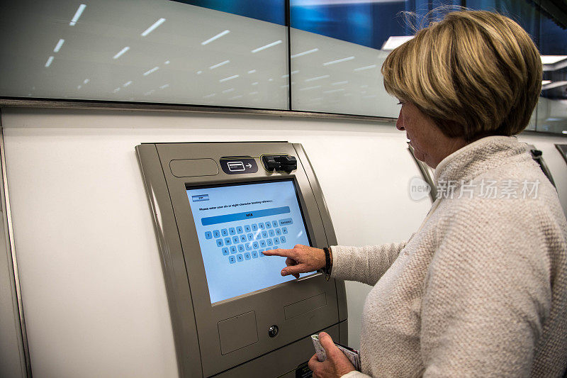 在伦敦圣潘克拉斯使用自动售票机的老妇人