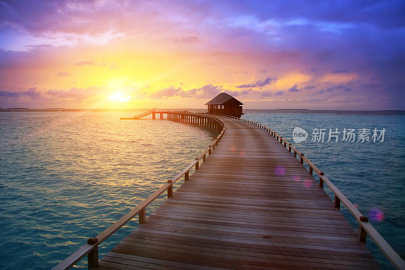日落时分，从岛上到水上小屋的木路。马尔代夫。