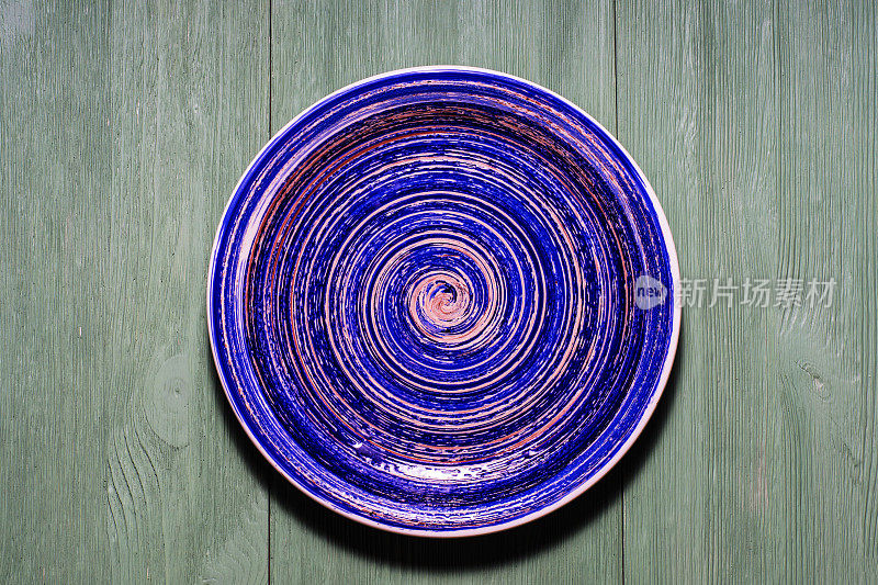 木制背景上的蓝色陶瓷釉面板。
