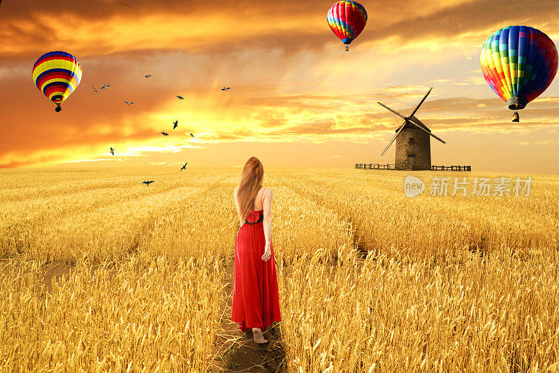赤着脚的年轻女子站在红裙子走过开阔的麦田，日出日落，天空，气球的背景。