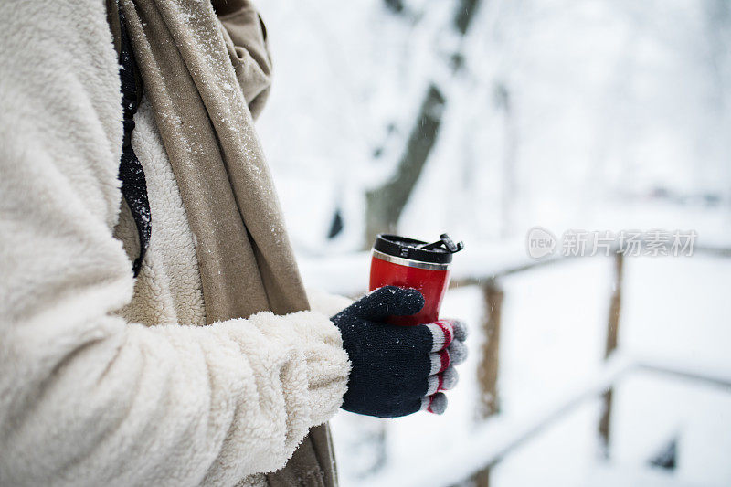 女人双手握着一杯热可可，茶或咖啡。冬季和圣诞节的时间概念。