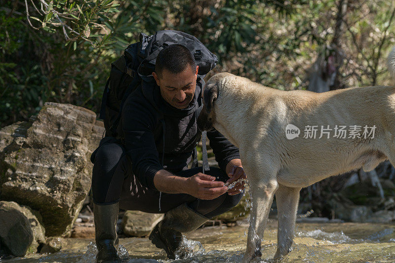 年轻男子洗她的狗从山河