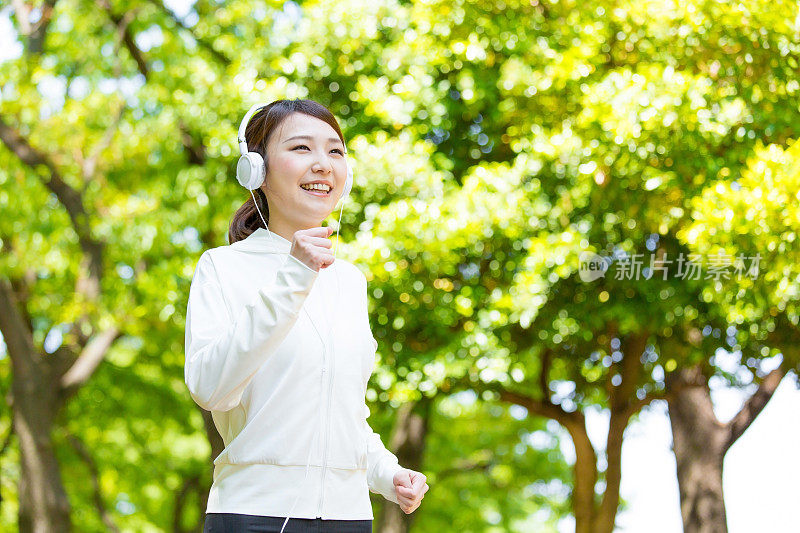 运动的亚洲女人在公园里跑步
