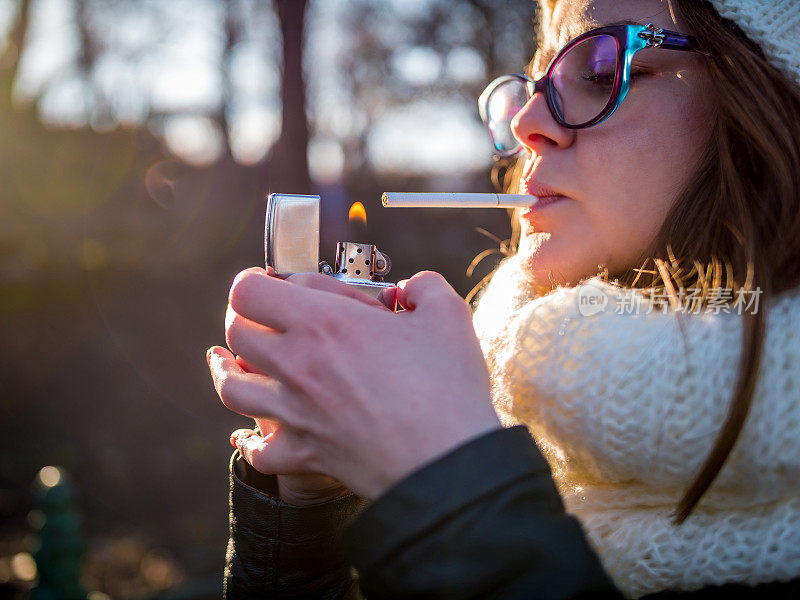 女孩在室外用金属打火机点烟