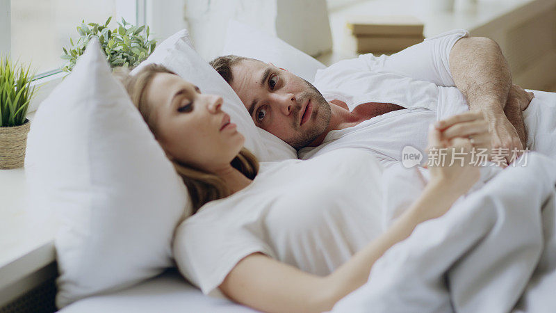 这是一对关系有问题的夫妇躺在家里的床上进行情感对话的特写