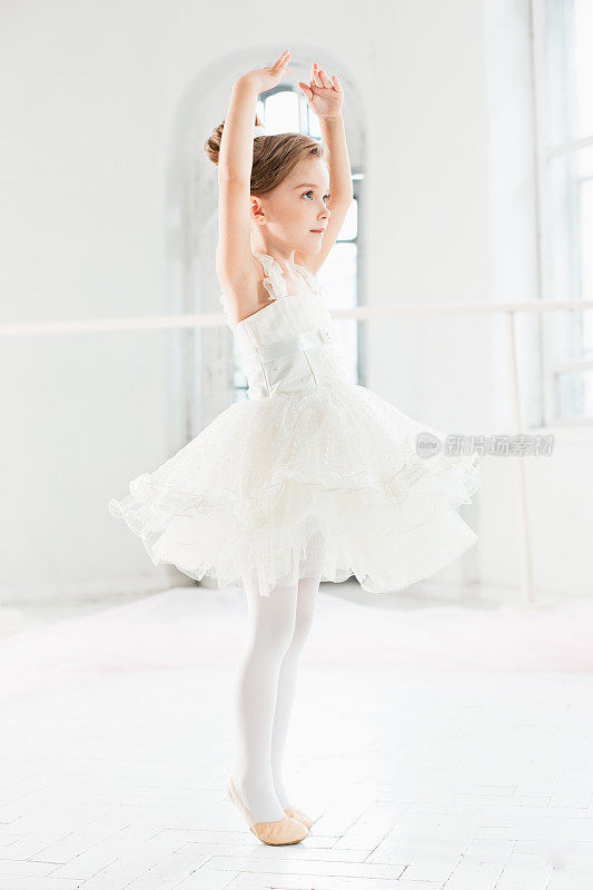 穿着芭蕾舞裙的小芭蕾舞女。可爱的孩子在一个白色的工作室里跳古典芭蕾