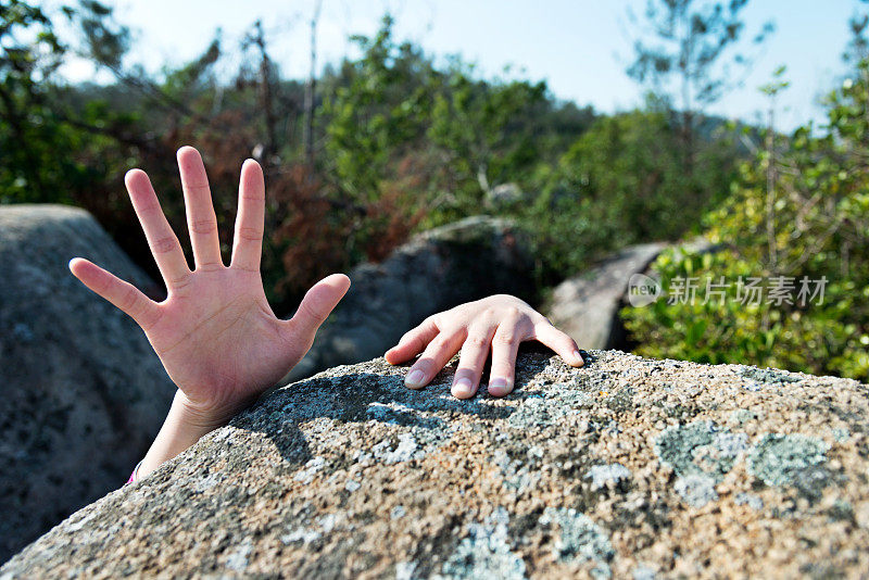 女人伸手在岩石上求助