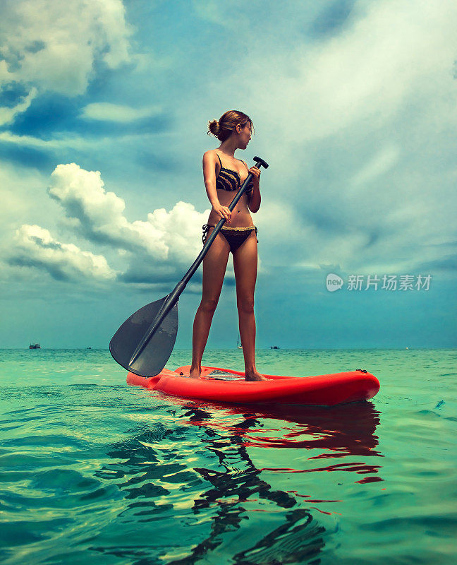 年轻苗条的女人在冲浪板上。积极的生活方式和水上运动。