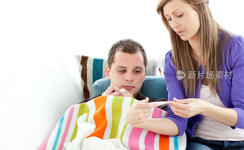 一个体贴的女人在白色背景下用温度计检查她生病的男朋友的温度