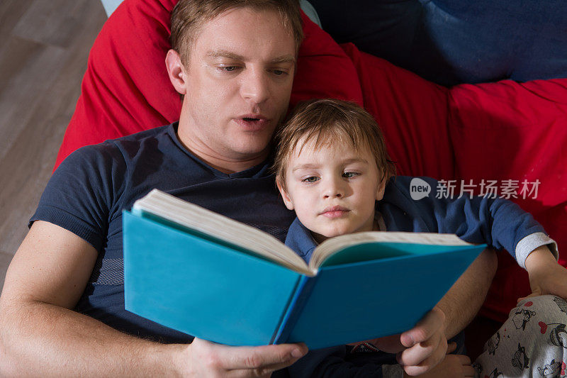 父亲给小儿子读故事。家庭团聚的快乐时光。