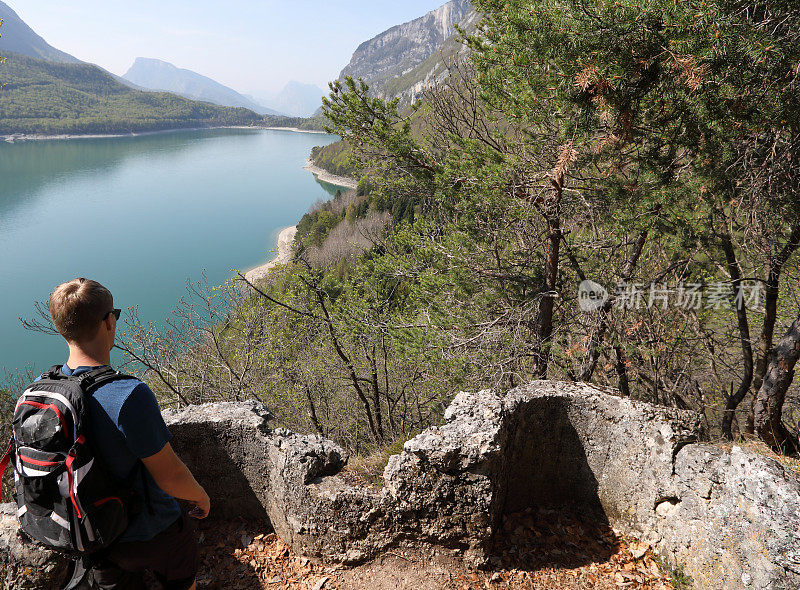 年轻人从古老的石墙Molveno看湖和山景