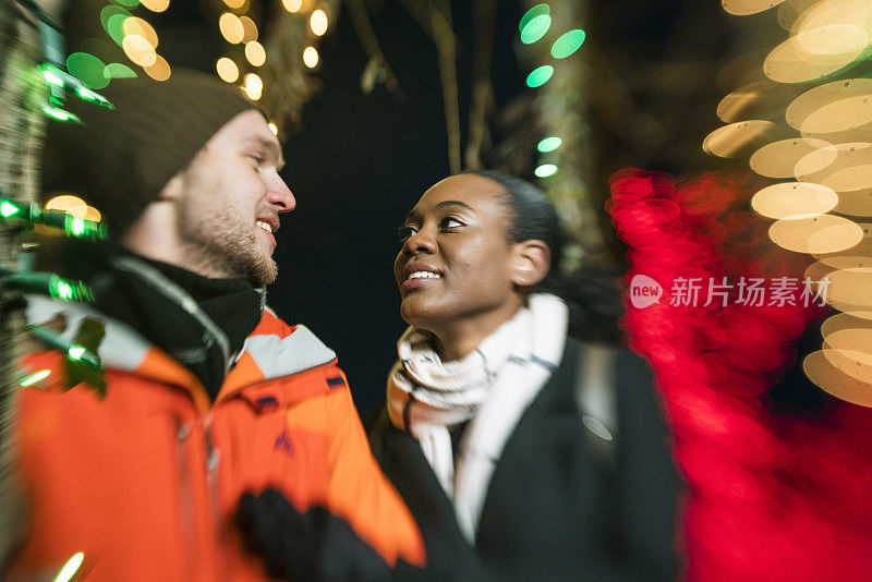 跨种族的相爱的夫妇，美丽的黑人年轻女子和英俊的年轻男子，在纽约布鲁克林观看圣诞彩灯和在寒冷的冬日里玩耍。