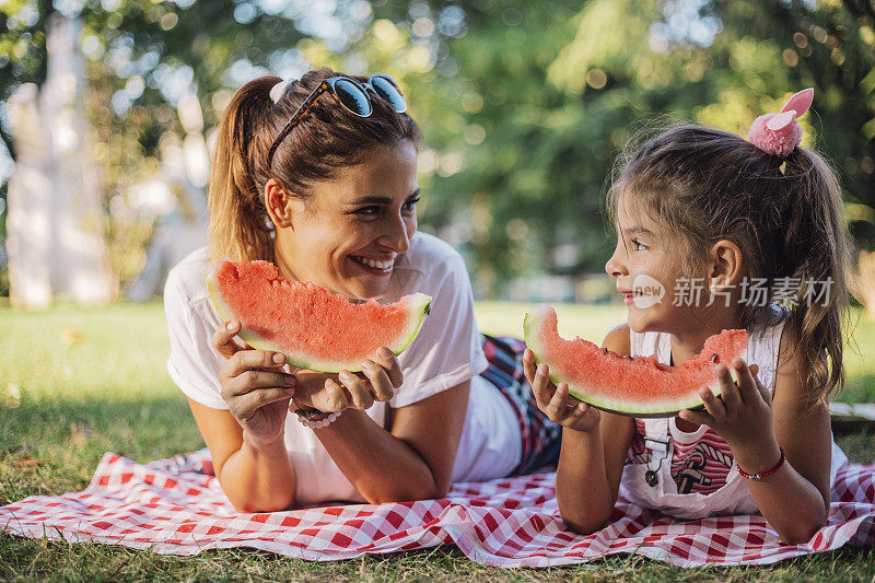 妈妈和女儿在公园里吃西瓜