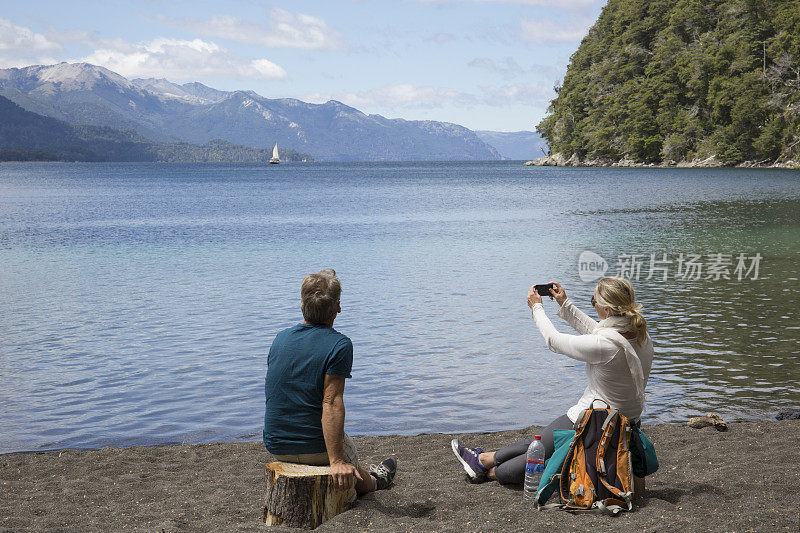 一对成熟的夫妇在山湖边的海滩上拍照