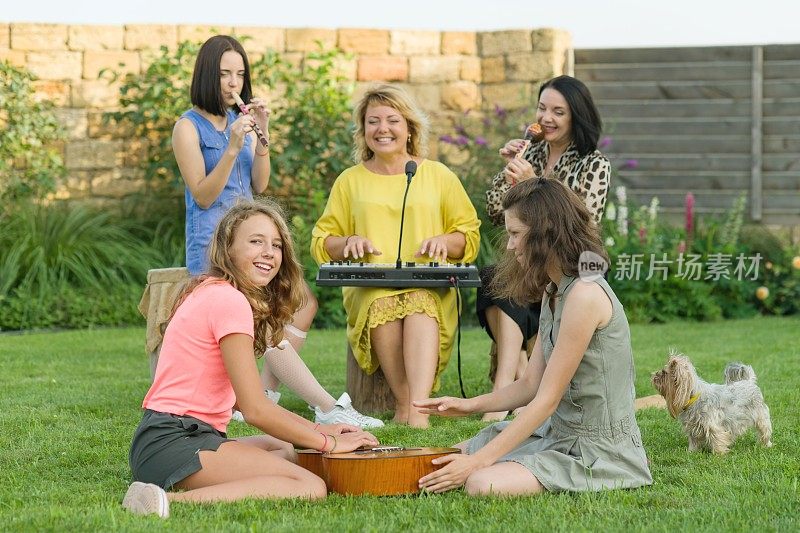 一家人玩得很开心，两个带着十几岁女儿的母亲在房子附近的草坪上唱歌和演奏乐器，还有家庭乐队