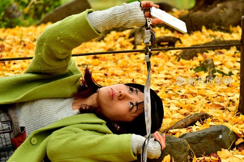 一名日本女子在秋天的银杏树下自拍