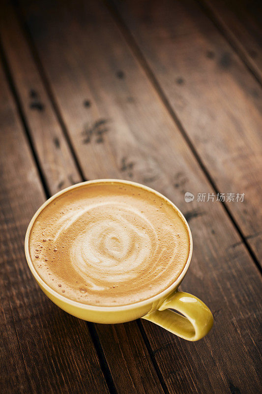 奶油拿铁咖啡与漩涡图案在一个古老的深色木头桌面上。