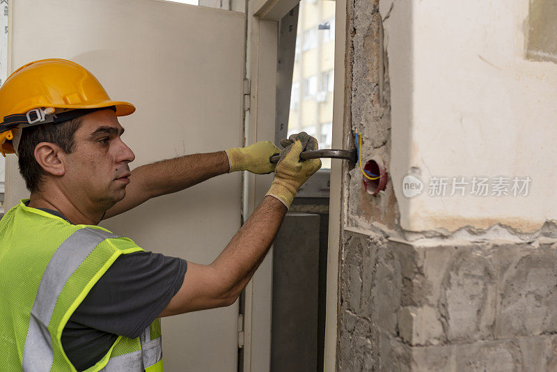 建筑工地的建筑工人正在用撬棍修门