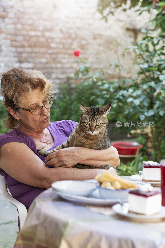 一位老妇人在户外抱着她的猫