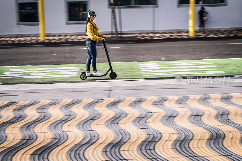 现代都市女性在大都市区的踏板车和自行车道上使用电动踏板车作为交通工具