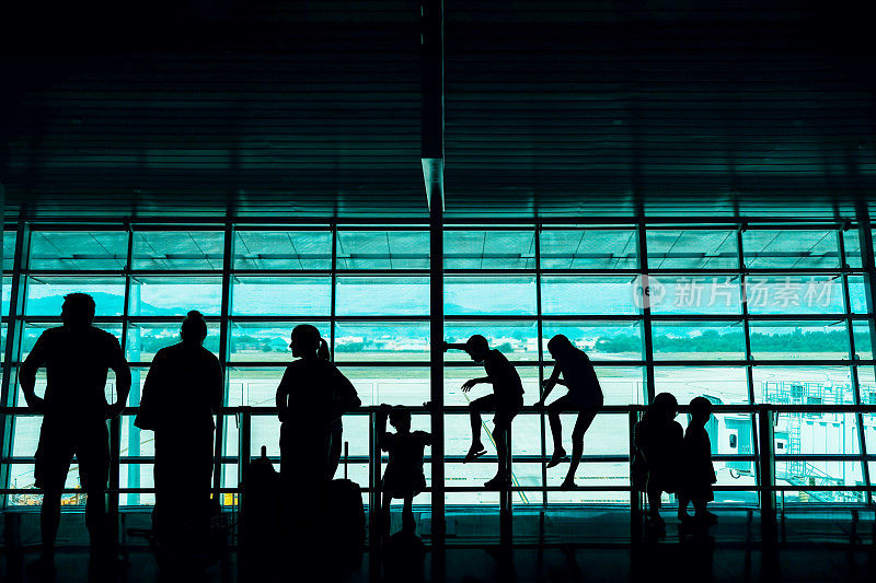 带着孩子旅行的概念。一个大家庭的乘客在机场的离港候机大厅等待登机的剪影