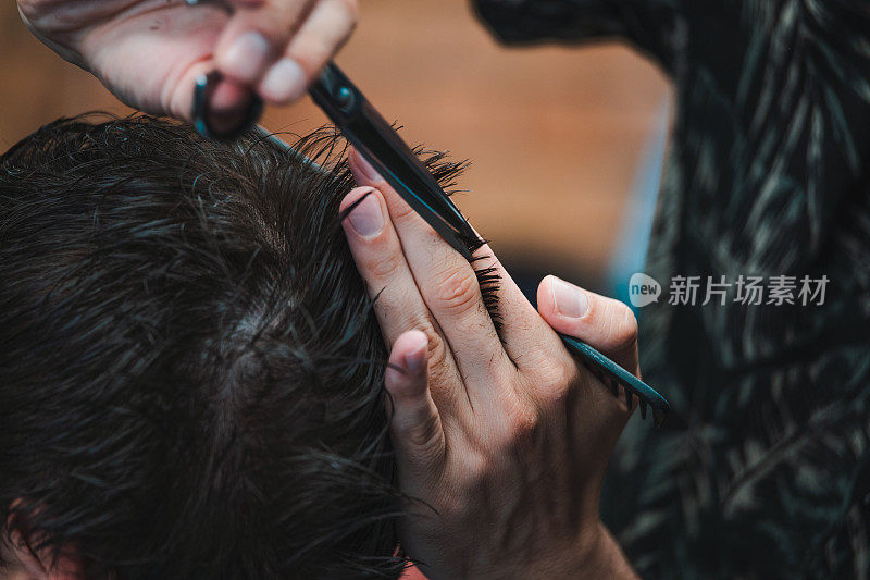 理发店。男人理发的特写，师傅在理发店里做发型。特写，大师理发师做的发型和造型与剪刀。理发店的概念。