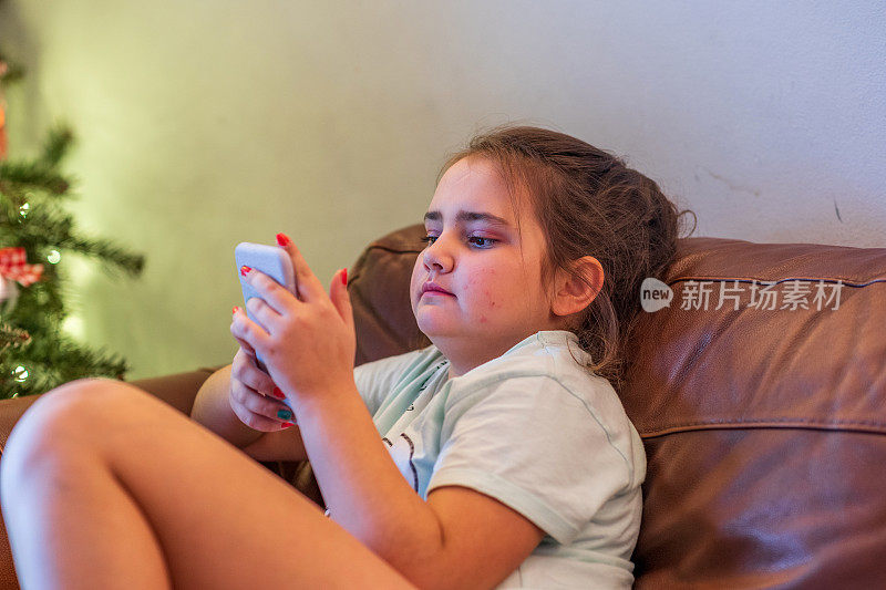 年轻女孩坐在沙发上玩手机