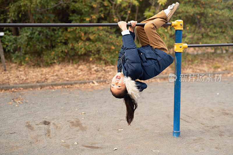 小女孩在公园里玩体操杆