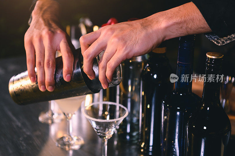 专业调酒师准备新鲜的酸橙柠檬水鸡尾酒在喝的葡萄酒杯与冰在晚上酒吧俱乐部柜台。职业与人们的生活方式观念。户外背景