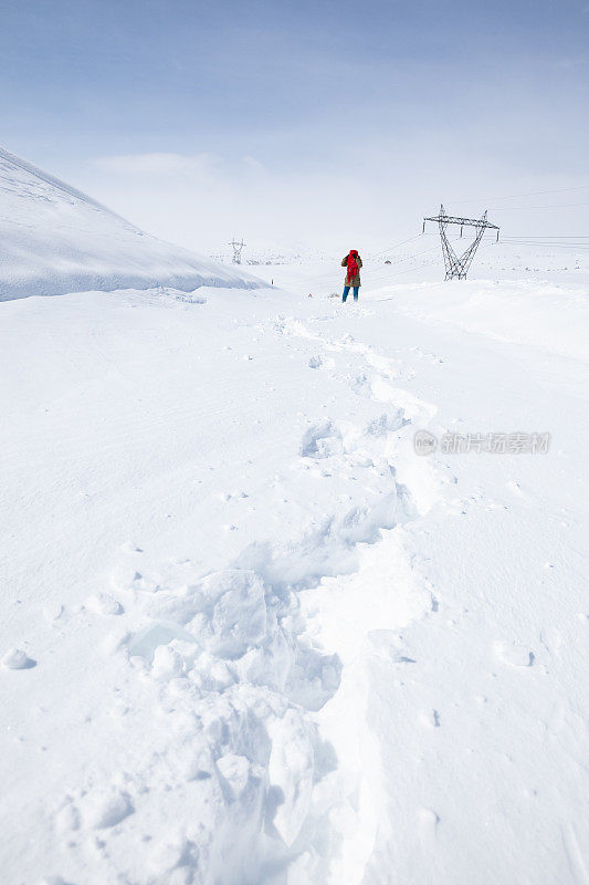 成年妇女穿着暖和的衣服在雪地上行走在农村