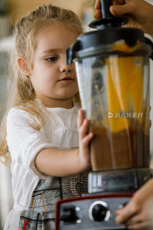 小女孩在帮助她的母亲调配原料，准备一道甜点