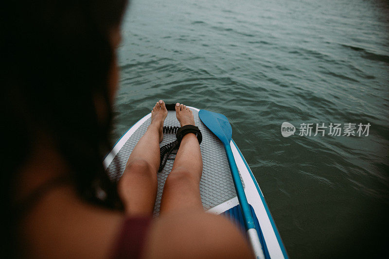 一名年轻女子在海中划桨板上休息