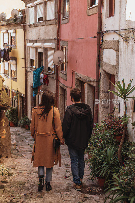 后视图的一个年轻夫妇散步和手牵手在波尔图老城的街道，葡萄牙