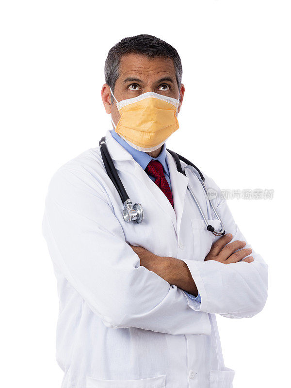 西班牙裔男医生穿着实验服，打着领带，戴着医用外科口罩，戴着听诊器，在白色背景下向上看