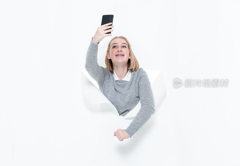 z一代的少女们穿着毛衣，用手机在白色背景前拍照