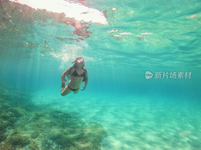 水下拍摄的一个年轻女孩浮潜在水晶蓝色的海洋