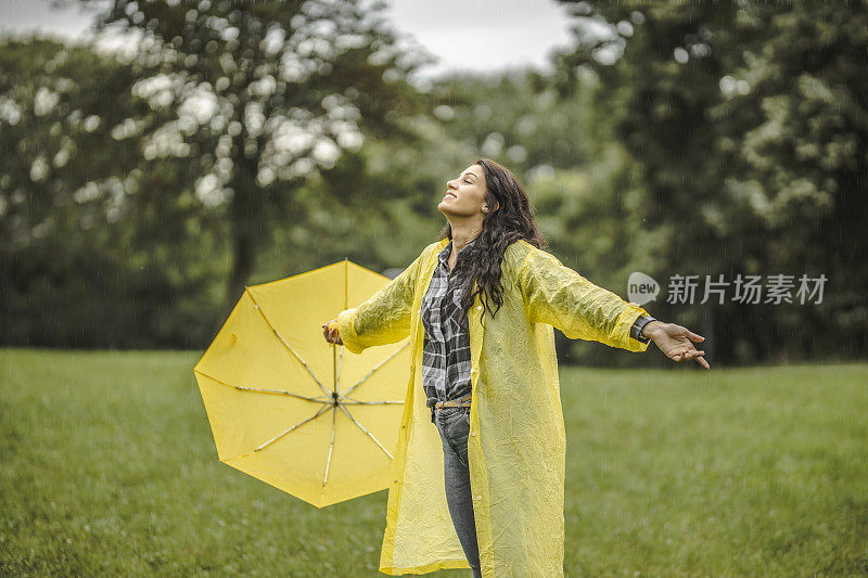 拿着黄伞，穿着黄雨衣，享受着雨的女人