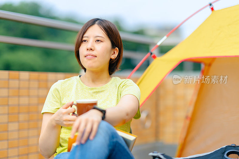 年轻女子放松喝热饮在阳台在家里