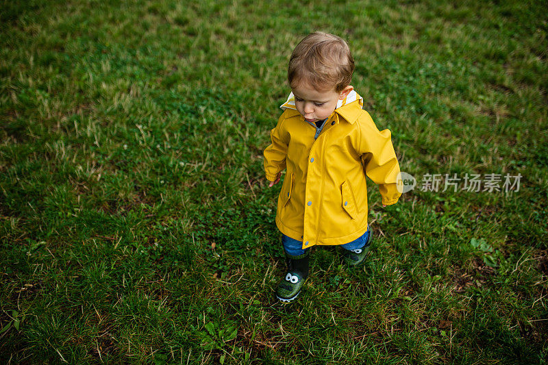 男孩在雨中玩耍，穿着靴子和雨衣